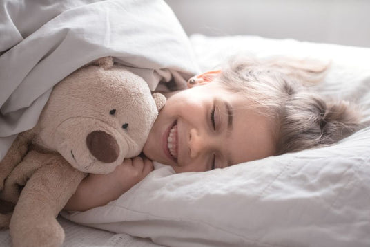 Blij kind in bed met haar verzwaringsknuffel