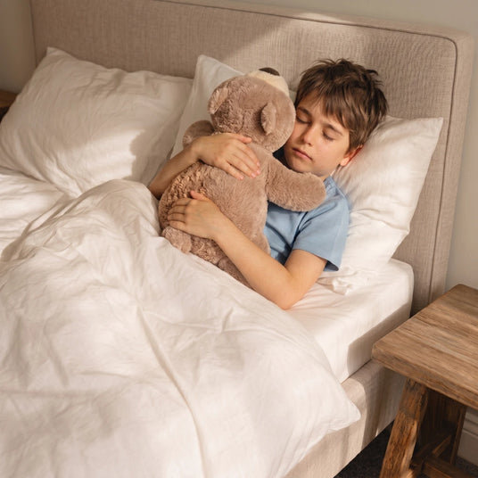 Kind in bed met verzwaringsknuffel aan het slapen