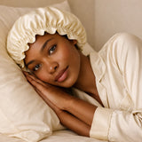 Vrouw ligt in bed met zijden bonnet beige