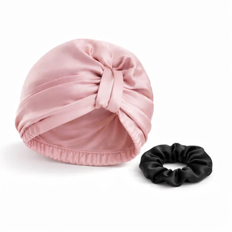 Bundel roze bonnet met zwarte scrunchie op witte achtergrond