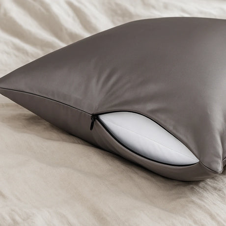 Grijs zijden kussensloop met ritssluiting op een bed